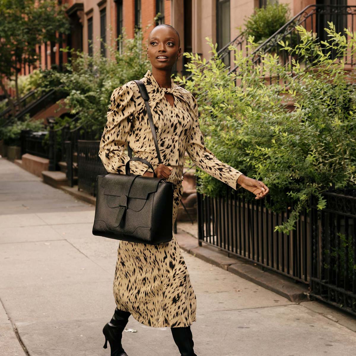 woman wearing a printed dress with a large vegan bag over her shoulder