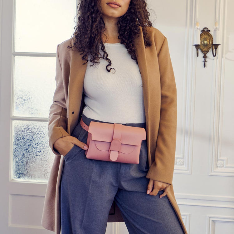 brown haired model wearing a coat and the pink aria as a belt bag
