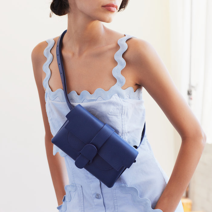 Model wearing light blue Rebecca Taylor sundress wears Pebbled Marine Aria Bag as crossbody belt bag