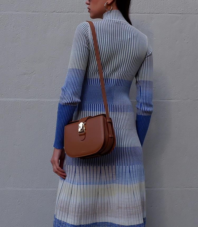 Woman wearing a striped sweater dress and the Cadence Crossbody in Chestnut over her shoulder