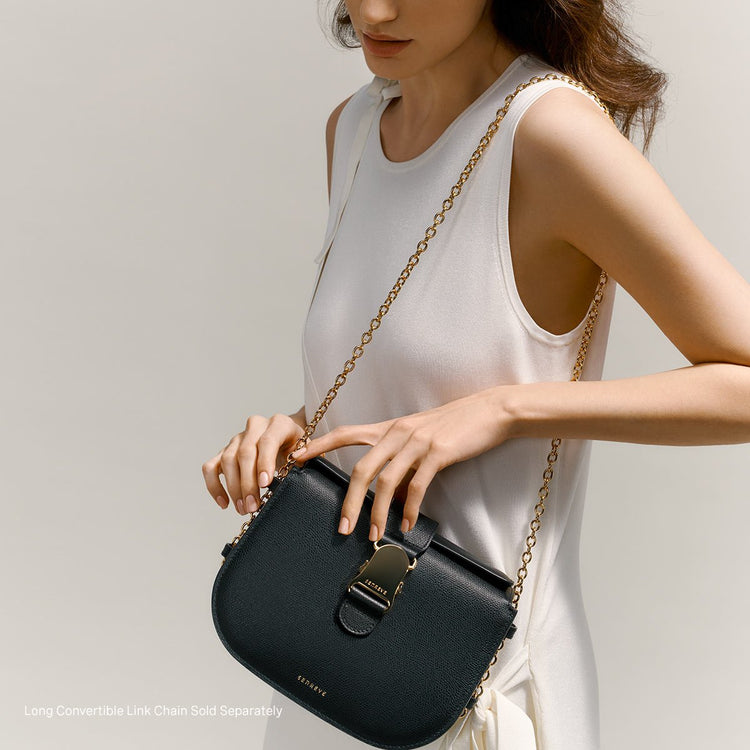 brunette model wearing a black crossbody bag over the shoulder with a gold chain
